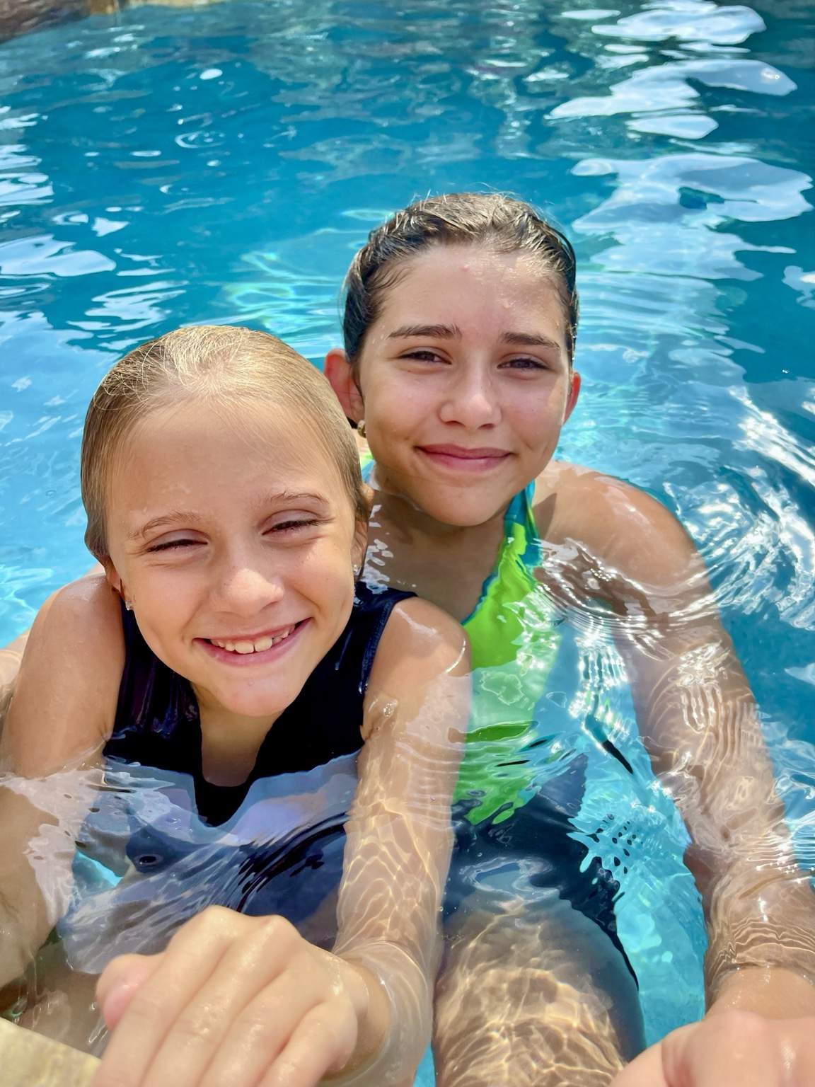 Two girls smiling together in the pool