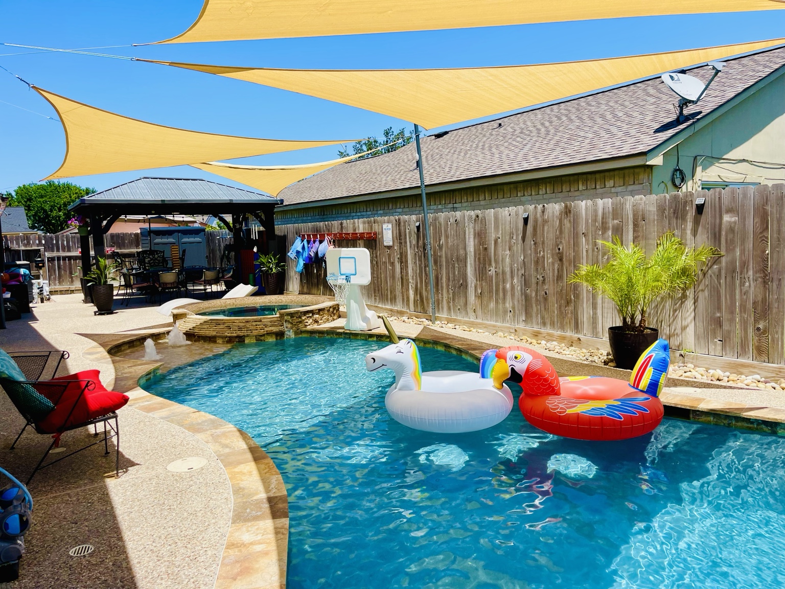 Bright daytime pool beneath large shade sails