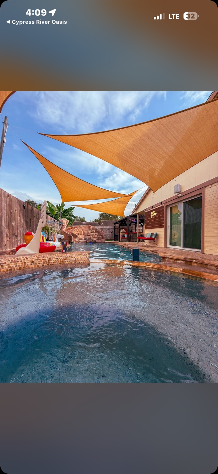 Long daytime view of the pool beneath layered shade sails