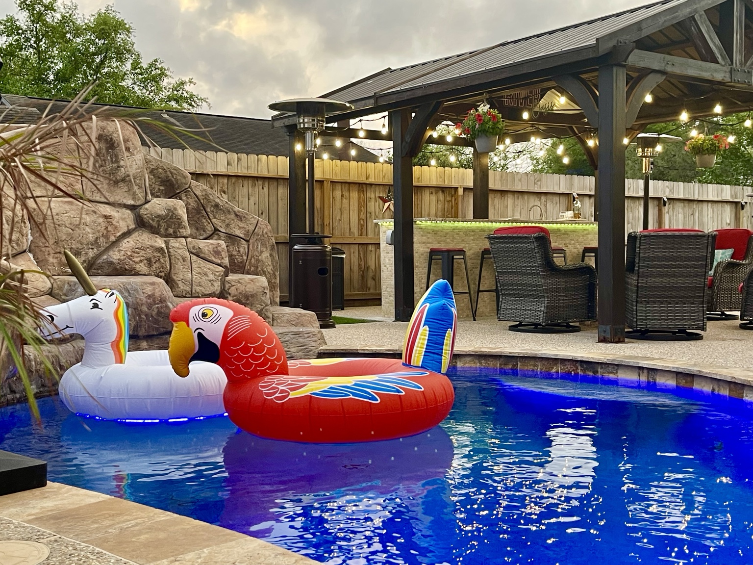 Illuminated pool floats and covered gazebo in the evening
