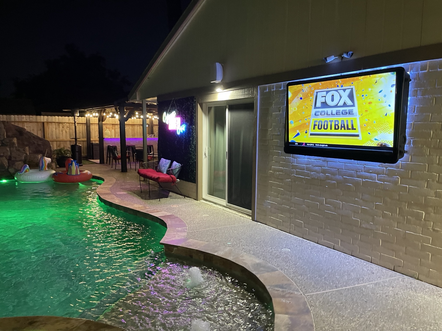 Outdoor television beside the illuminated swimming pool at night