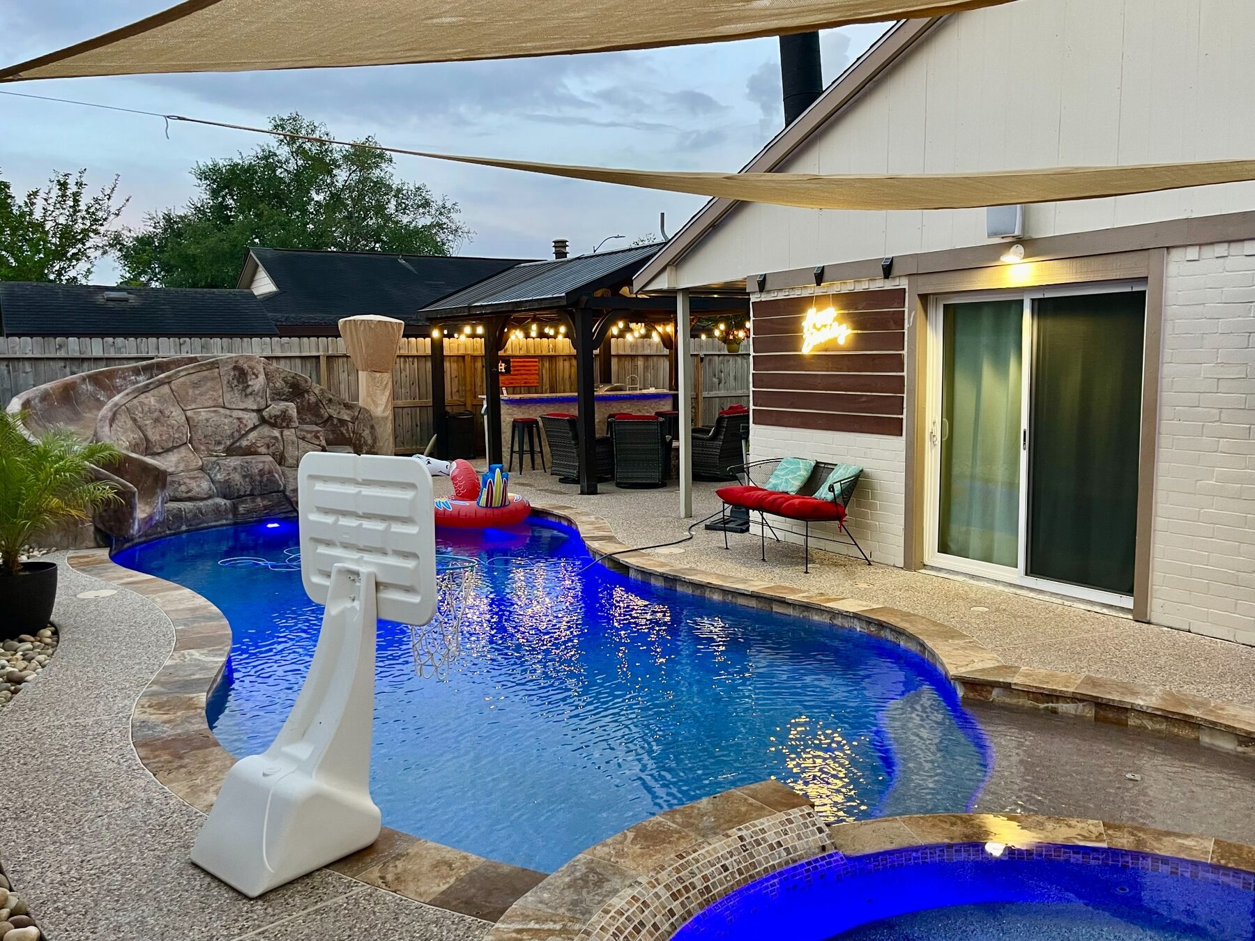 Illuminated pool and raised hot tub in the evening