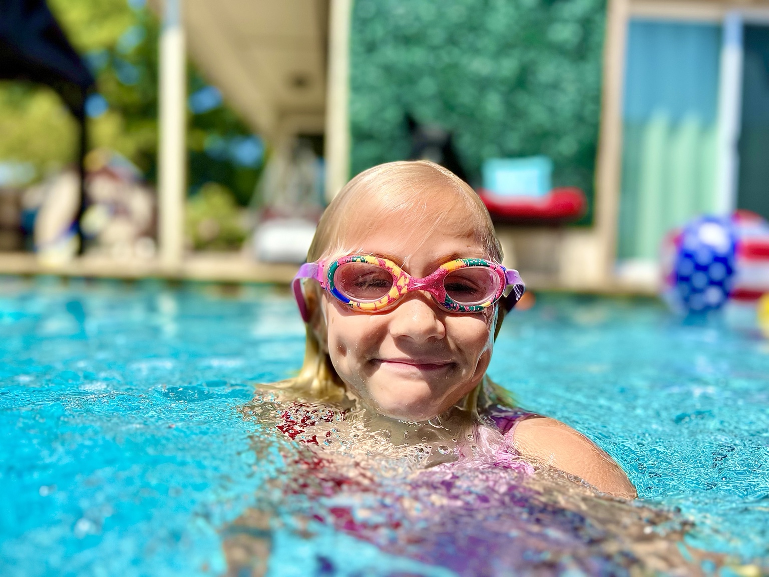 Smiling child in colorful goggles enjoying the pool