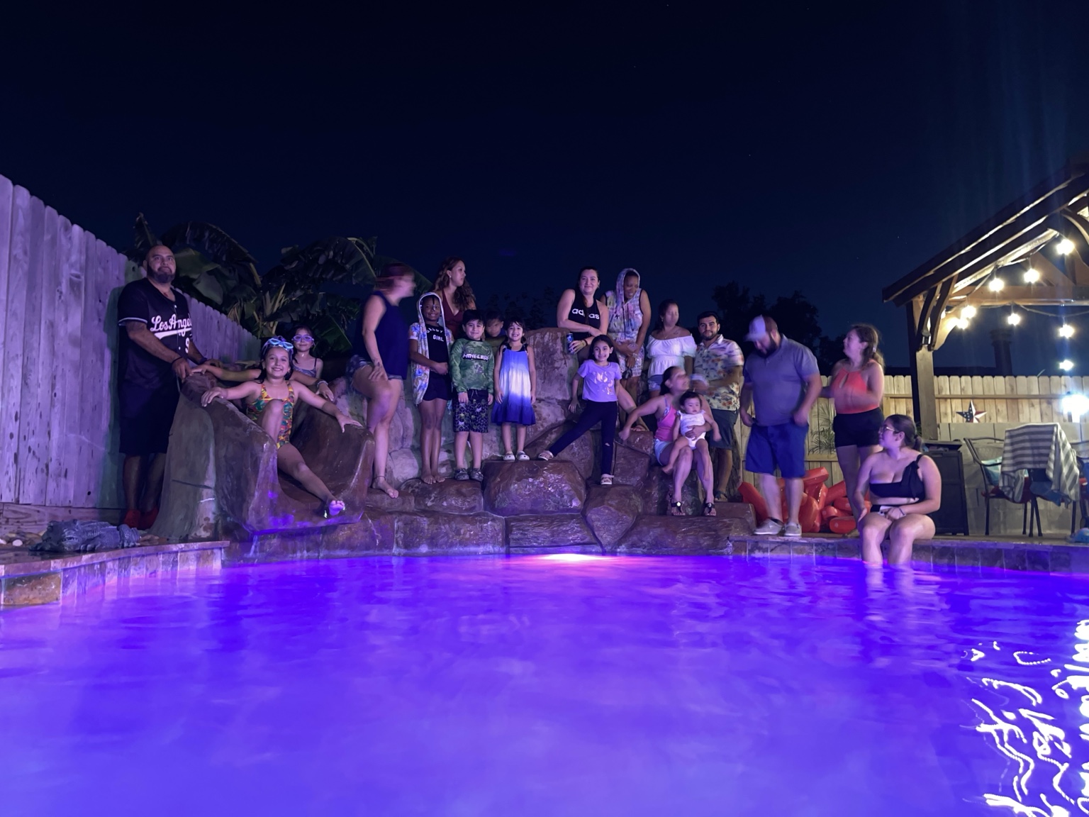 Family group gathered around the illuminated pool at night