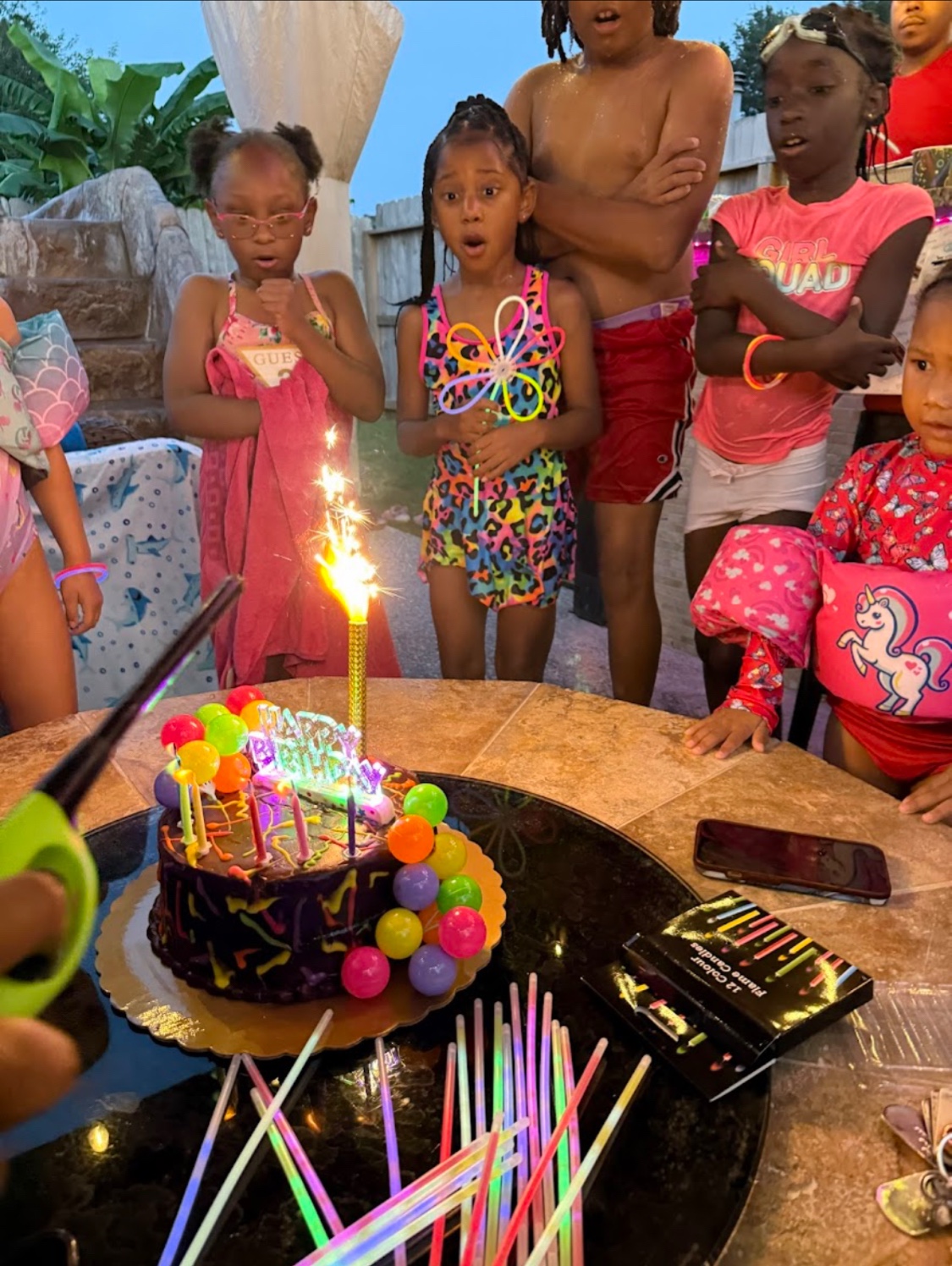 Children gathered around a birthday cake and sparkling candle at Cypress River Oasis